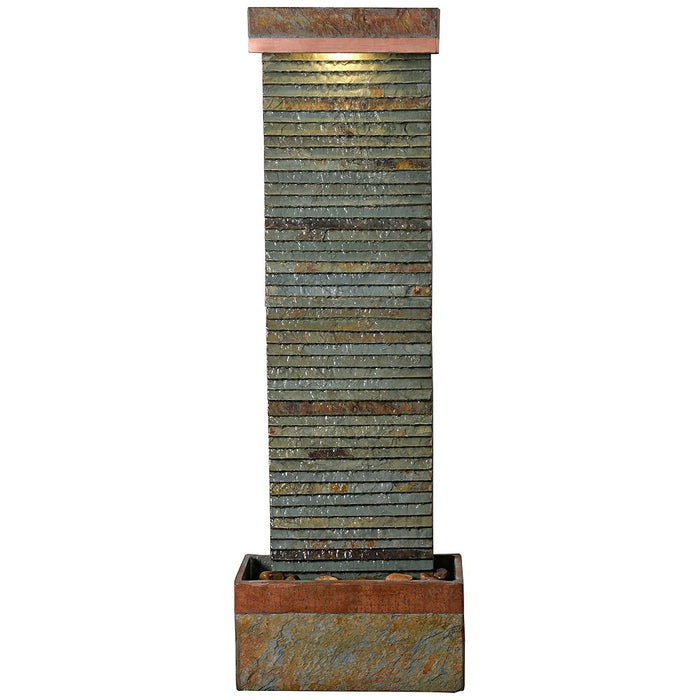 Full view of tall slate water fountain with ribbed stone texture, copper trim, and warm LED lighting at the top.