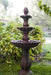 A 3-tier bird bath fountain in rust in a garden setting.