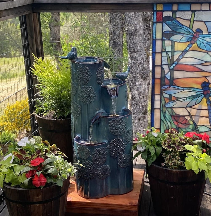 A dandelion themed water feature near pot plants.