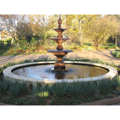 A cast iron water fountain with pond in a garden.
