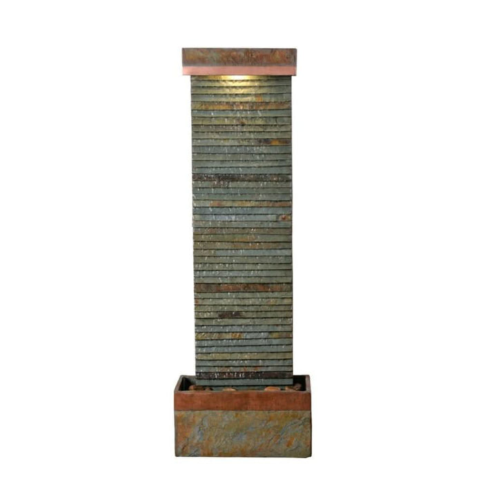 Full view of tall slate water fountain with ribbed stone texture, copper trim, and warm LED lighting at the top.