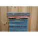 Top section of a slate water feature with copper edging and layered stone texture, set against a timber fence.