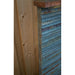 Side view of a tiered slate water feature with textured stone layers and copper trim against a wooden fence.