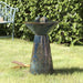 A ceramic birdbath fountain on grass.