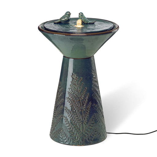 An abstract ceramic birdbath fountain with etched leaves.