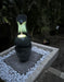 Mirage water fountain with a pebble surround in a beautifully landscaped garden setting.