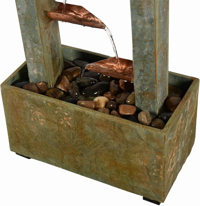 Slate water fountain base with copper spouts pouring water over decorative river stones