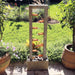 Outdoor slate water fountain with copper spouts cascading into a stone-filled base, set in a garden.