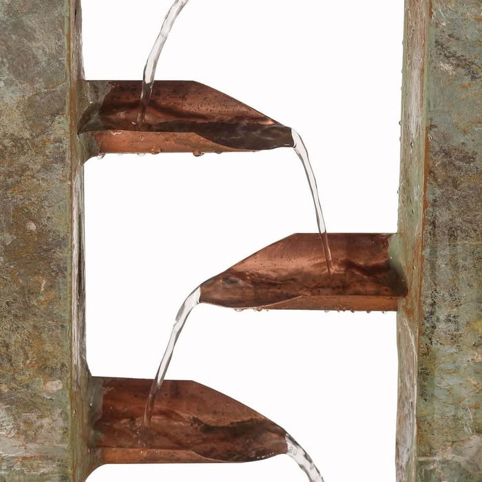 Close-up of copper spouts on a slate water fountain with water flowing between tiers.