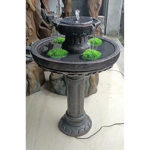 A bird bath fountain with plants in the bowl.