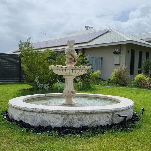 A concrete fountain with cherub boy within a pond.
